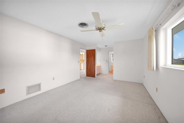 unfurnished bedroom with light carpet, connected bathroom, visible vents, and a ceiling fan