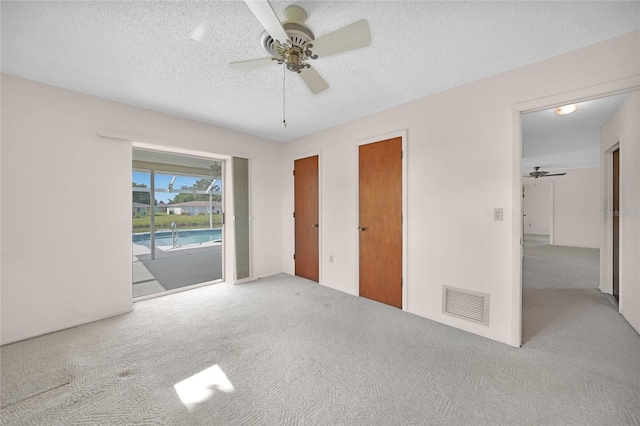 unfurnished bedroom featuring light carpet, access to outside, visible vents, and a textured ceiling