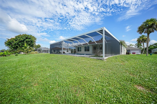 rear view of house with a lawn and a lanai