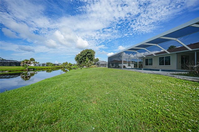 view of yard featuring a carport, glass enclosure, and a water view