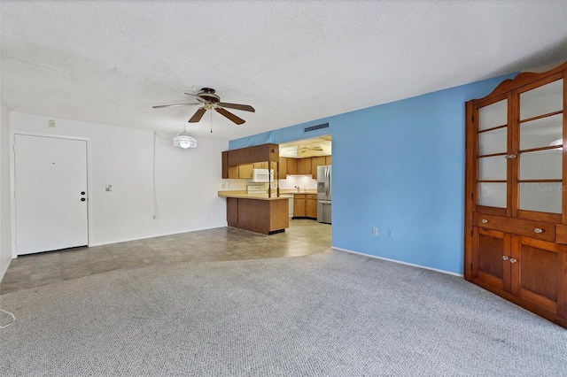 unfurnished living room featuring a textured ceiling, ceiling fan, and light colored carpet