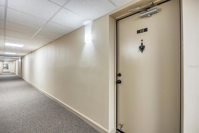 corridor with a paneled ceiling and carpet flooring