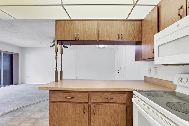 kitchen featuring a textured ceiling, white appliances, ceiling fan, and kitchen peninsula