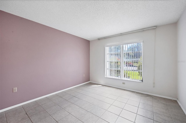 unfurnished room with a textured ceiling and light tile patterned floors