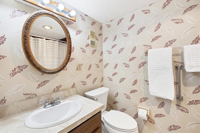 bathroom featuring a textured ceiling, vanity, and toilet