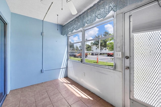 doorway with ceiling fan, a textured ceiling, plenty of natural light, and light tile patterned floors