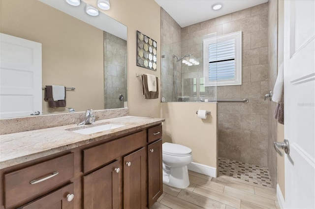 bathroom with tile patterned floors, vanity, a tile shower, and toilet