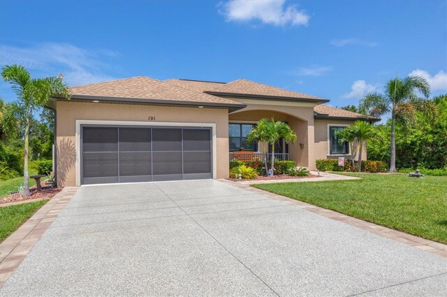 191 Brig Cir W, Placida, FL 33946 - view of front of property with an attached garage, concrete driveway, a front lawn, roof with shingles, and stucco siding