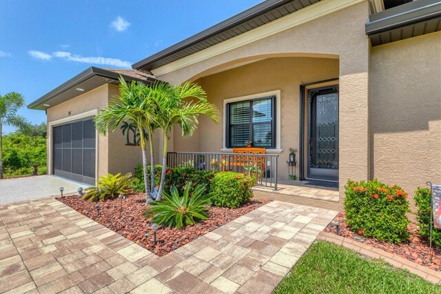 191 Brig Cir W, Placida, FL 33946 - doorway to property with covered porch, a garage, driveway, and stucco siding