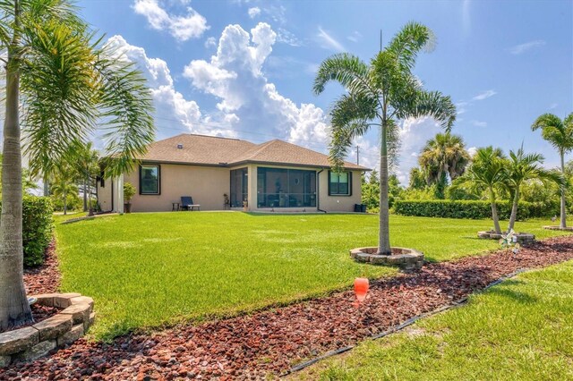 191 Brig Cir W, Placida, FL 33946 - rear view of house featuring stucco siding and a yard