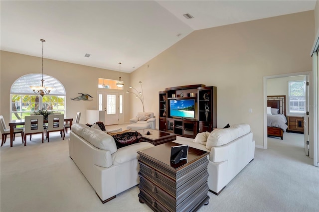 living room with high vaulted ceiling, an inviting chandelier, and light carpet