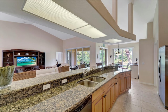 kitchen with dark stone counters, stainless steel refrigerator, vaulted ceiling, light tile patterned floors, and sink