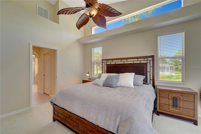 carpeted bedroom featuring ceiling fan and a towering ceiling