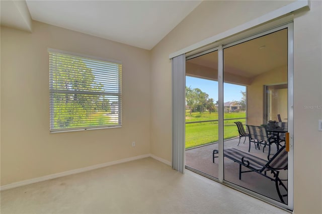 carpeted spare room featuring a wealth of natural light and vaulted ceiling