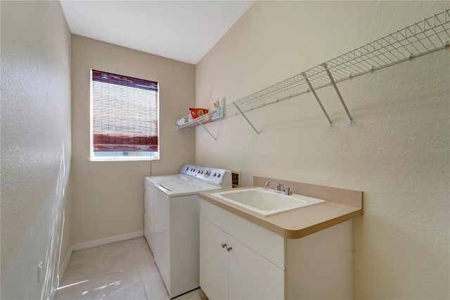 clothes washing area featuring separate washer and dryer, sink, light tile patterned flooring, and cabinets