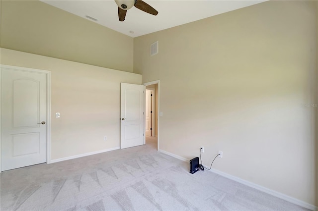 unfurnished bedroom featuring ceiling fan, a towering ceiling, and light colored carpet