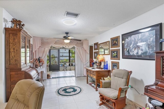 living area featuring a textured ceiling, ceiling fan, and light tile patterned floors