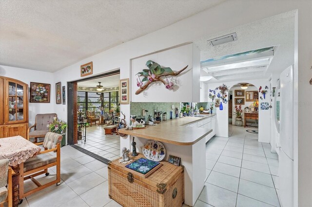 kitchen with ceiling fan, a textured ceiling, light tile patterned floors, and white fridge