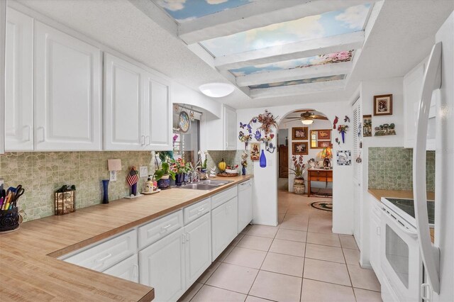 kitchen with ceiling fan, backsplash, white cabinetry, sink, and stove