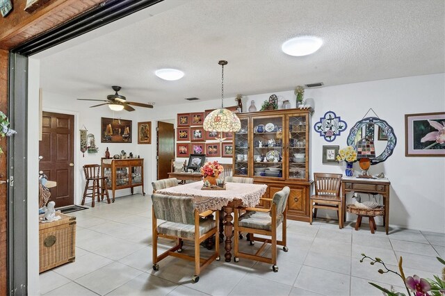 dining area with ceiling fan, light tile patterned floors, and a textured ceiling