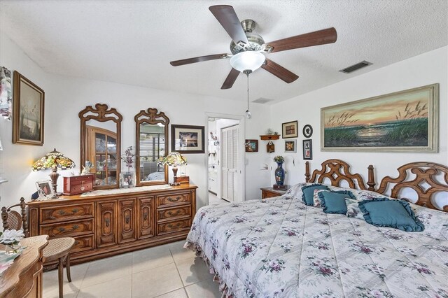 bedroom with a textured ceiling, ceiling fan, and light tile patterned floors