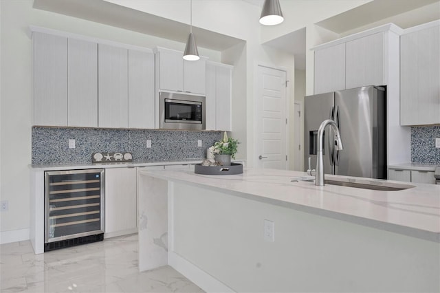 kitchen with wine cooler, appliances with stainless steel finishes, hanging light fixtures, marble finish floor, and a sink