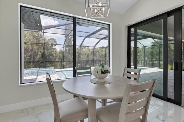 dining room featuring a sunroom, plenty of natural light, marble finish floor, and baseboards