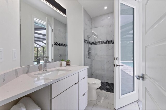 bathroom featuring toilet, vanity, and a tile shower