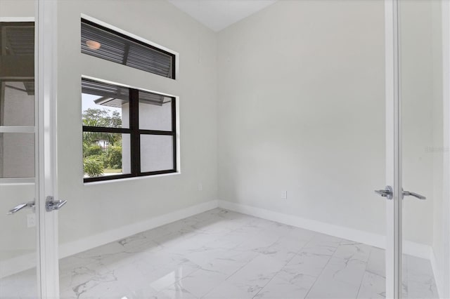 unfurnished room featuring marble finish floor, french doors, and baseboards