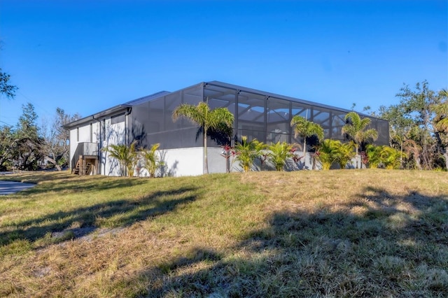 view of property exterior with glass enclosure and a yard