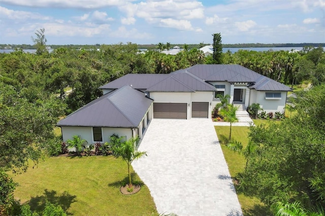 view of front of house with a front yard, a garage, and a water view