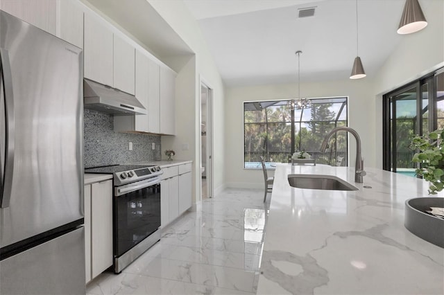 kitchen featuring lofted ceiling, light stone countertops, appliances with stainless steel finishes, and hanging light fixtures