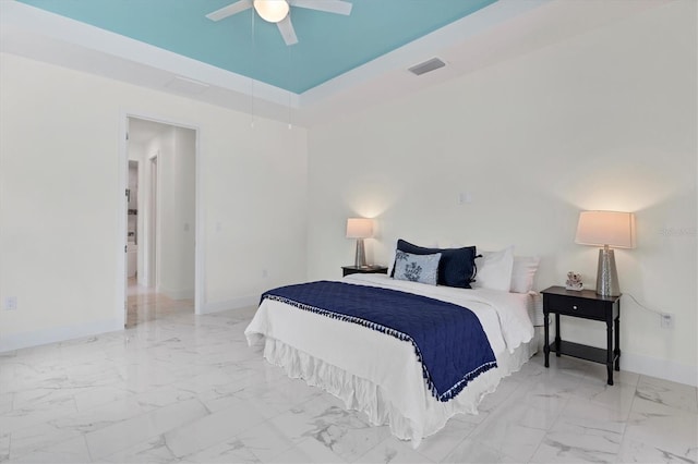 bedroom featuring a ceiling fan, visible vents, baseboards, marble finish floor, and a tray ceiling