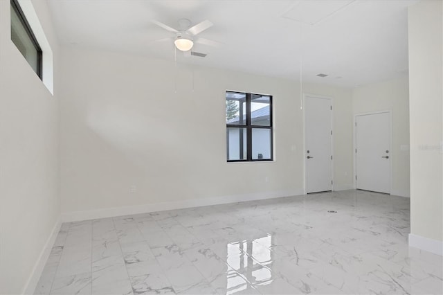 empty room with marble finish floor, baseboards, and a ceiling fan