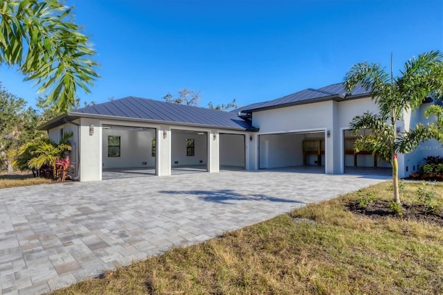 view of front of property featuring metal roof, a garage, decorative driveway, stucco siding, and a standing seam roof