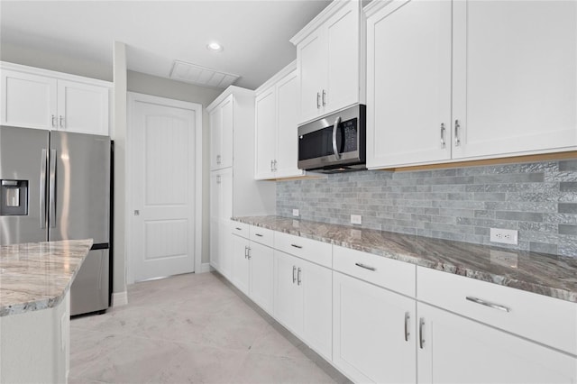 kitchen with white cabinetry, backsplash, light stone counters, appliances with stainless steel finishes, and light tile patterned flooring