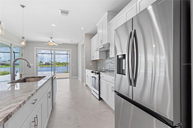 kitchen with appliances with stainless steel finishes, tasteful backsplash, sink, light stone countertops, and light tile patterned floors