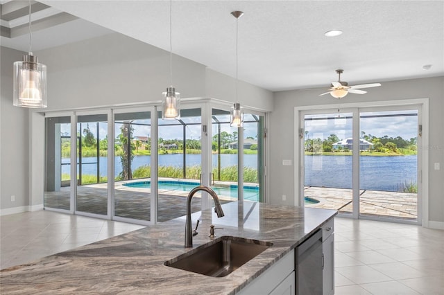 kitchen with sink, dark stone countertops, a water view, and dishwashing machine