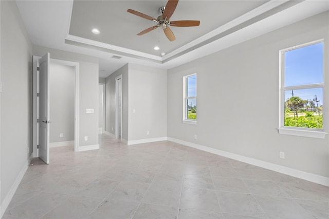 spare room featuring a raised ceiling and ceiling fan