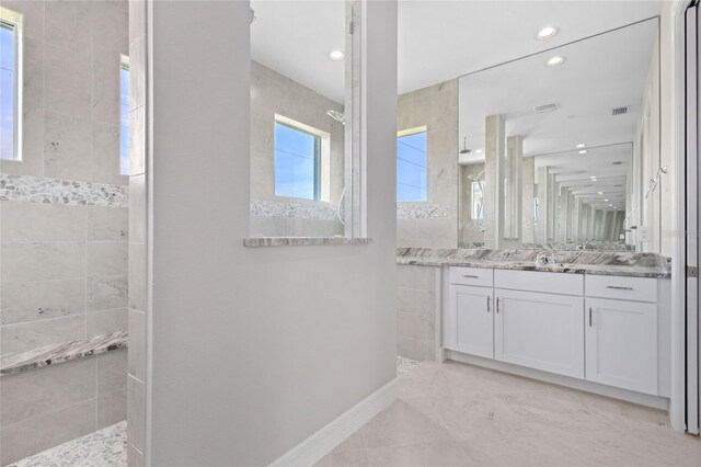 bathroom featuring a tile shower, tile patterned floors, and vanity