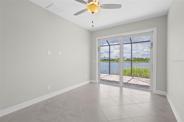 tiled empty room with ceiling fan and a water view