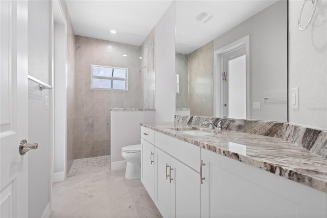 bathroom featuring vanity, tiled shower, and toilet