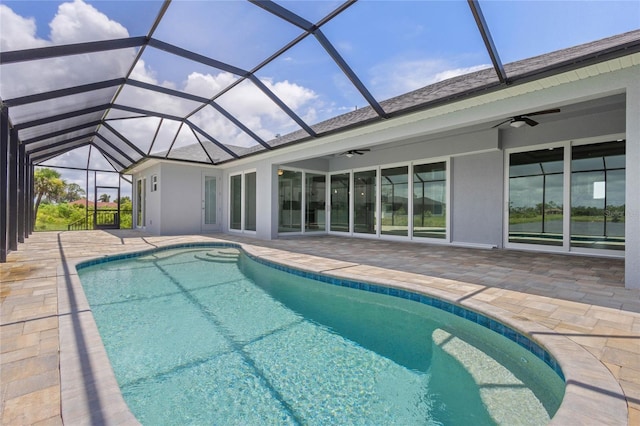 view of swimming pool with glass enclosure, ceiling fan, and a patio area