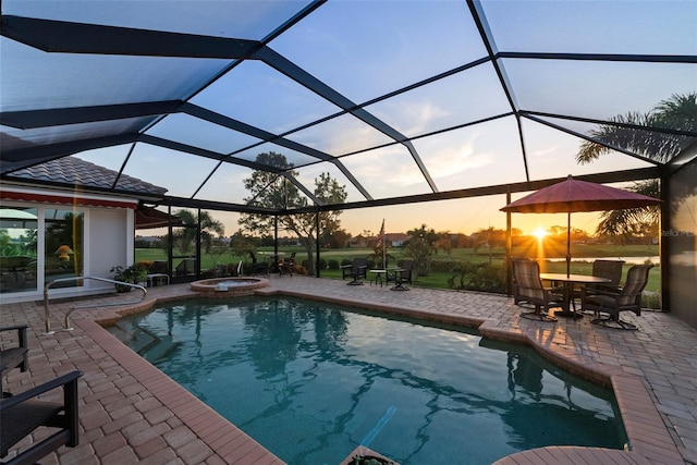 pool at dusk featuring a patio area, a lanai, and an in ground hot tub