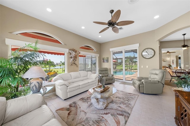 living area with light tile patterned floors, arched walkways, a ceiling fan, and recessed lighting