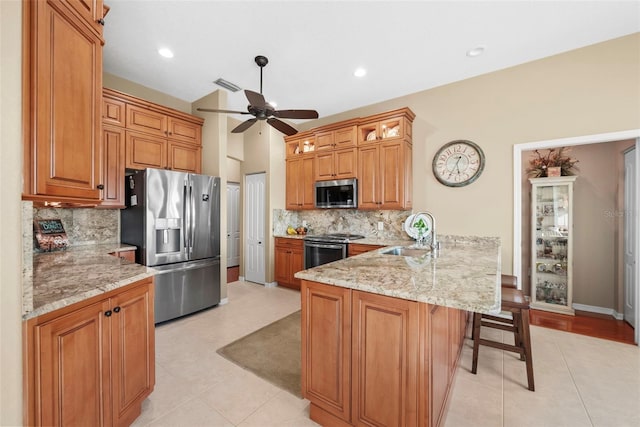 kitchen featuring ceiling fan, backsplash, appliances with stainless steel finishes, sink, and kitchen peninsula