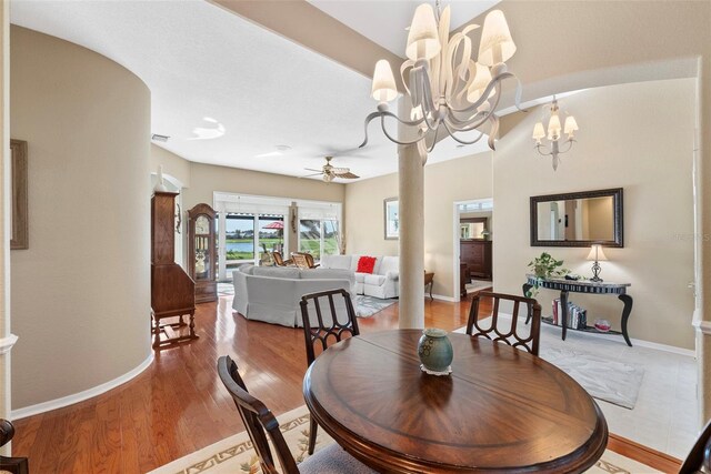 dining area featuring ceiling fan with notable chandelier and wood-type flooring