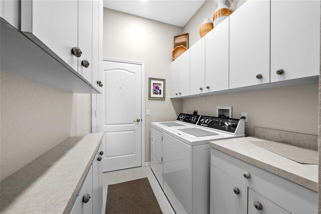 laundry room with washer and dryer, cabinets, and light tile patterned floors