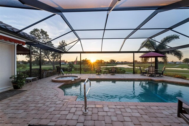 pool at dusk with an in ground hot tub, a patio area, and a lanai