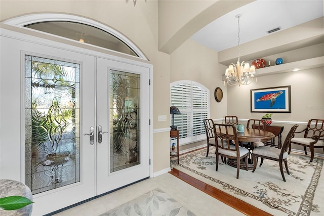 interior space with baseboards, visible vents, arched walkways, an inviting chandelier, and french doors